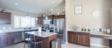 A modern kitchen with a central island, stainless steel appliances, and a dining area with bar stools.