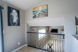 A staircase with a metal railing, a painting of a horse, and a landscape painting above it. - Your Home Away from Home (Omaha)