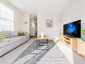 Ein modernes Wohnzimmer mit einer Couch, einem Couchtisch, einem Fernseher und einem Bücherregal.