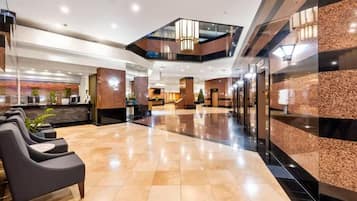 A hotel lobby with a reception desk, seating area, and a modern staircase.