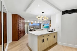 A modern kitchen with a central island, wooden cabinets, and a view of the outdoors. - 22F-Upscale & Modern-Financial District-Harbor View-1 Bedroom Condo w/Parking (Honolulu)