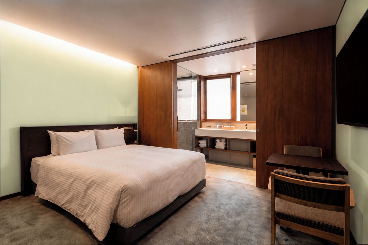 Et moderne soveværelse med en stor seng, et natbord, en stol og en indbygget garderobe.