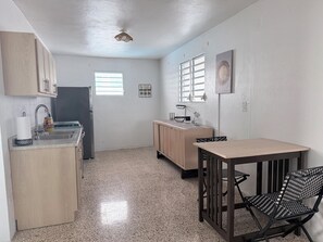 Cocina compacta con comedor, armarios de madera, un refrigerador y un ventilador de techo.