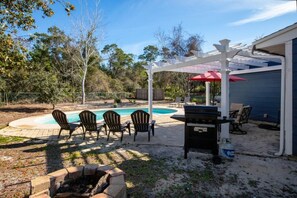 A backyard with a swimming pool, patio furniture, a barbecue grill, and a pergola with a red umbrella. - Miramar Home with Private Pool, Large Deeded Beach Access, Bikes & Paddleboards (Miramar Beach)