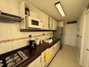 Cozinha equipada com fogão, micro-ondas e frigorífico.