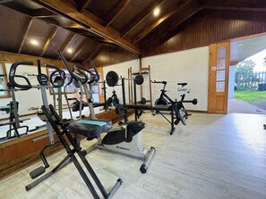 Un gimnasio con varios equipos de ejercicio, incluyendo una prensa de banca, máquinas de pesas y una bicicleta estática.