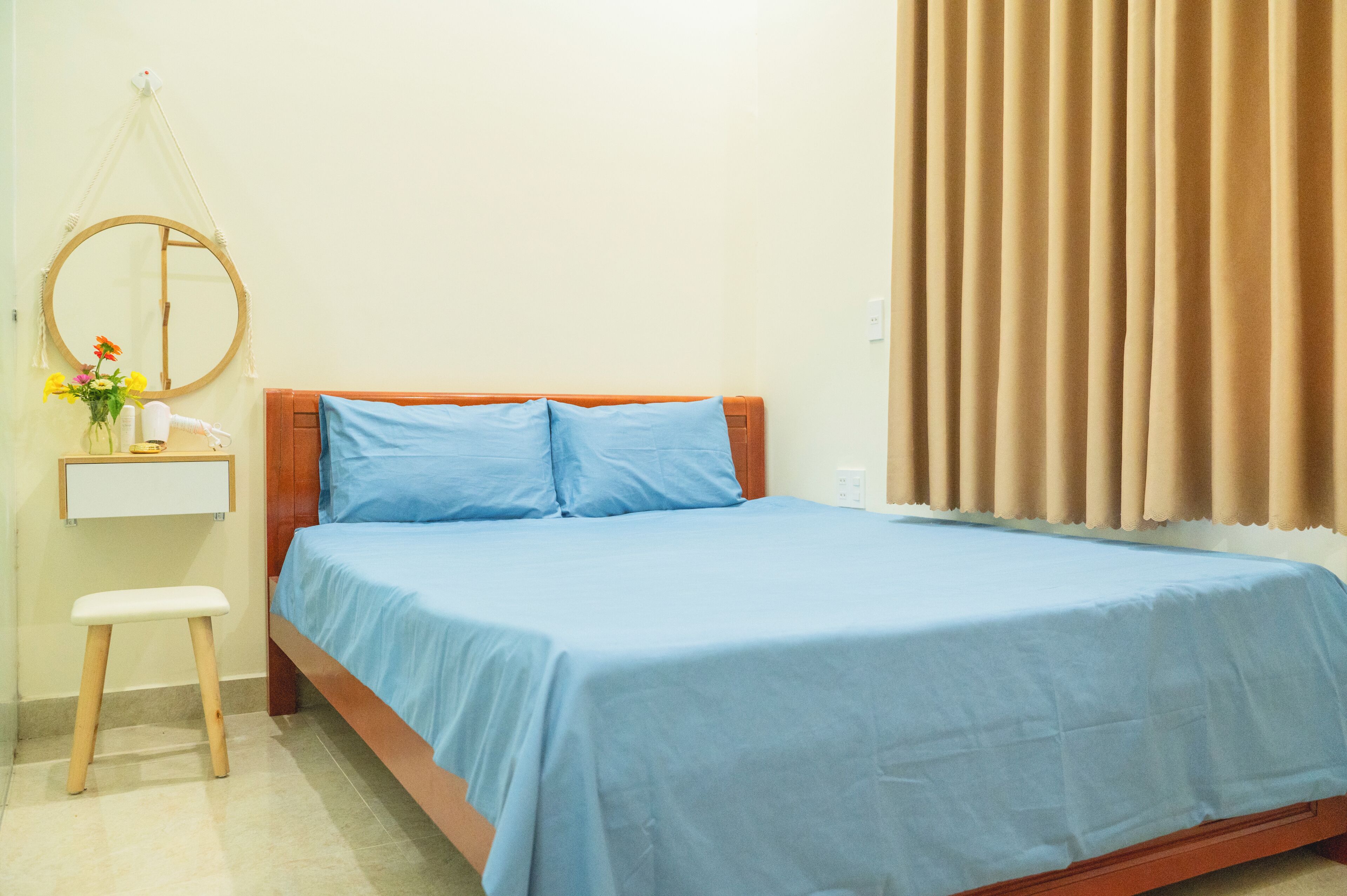 Un dormitorio con una cama, una mesita de noche, un espejo y una ventana con cortinas.