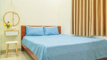 Un dormitorio con una cama, una mesita de noche, un espejo y una ventana con cortinas.