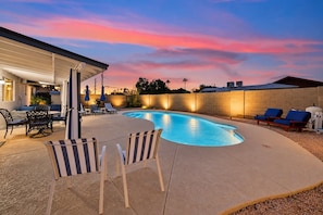 A swimming pool with lounge chairs and a covered patio area. - Campus Palms | Modern 3BR | Private Pool (Tempe)