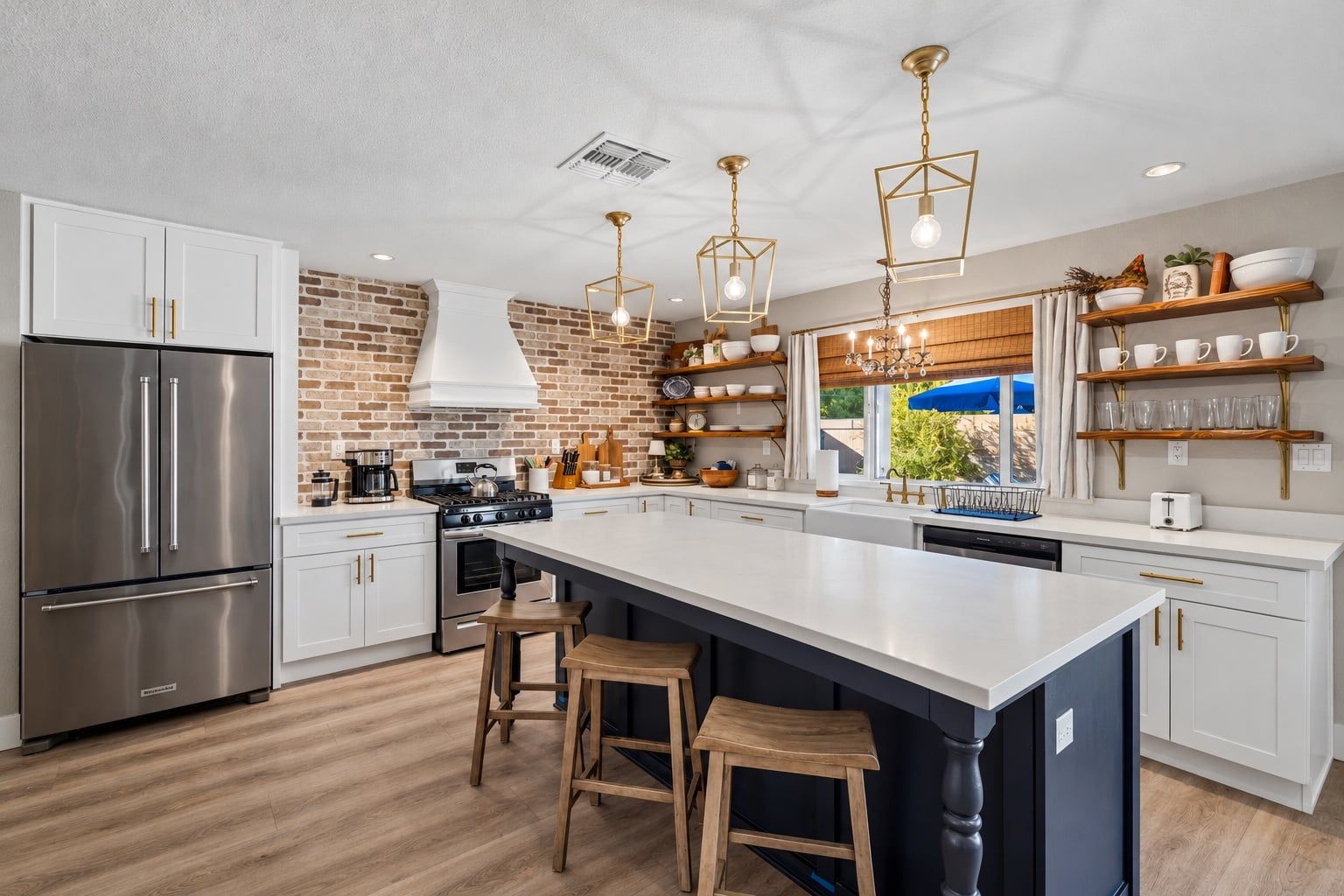 A modern kitchen with a large island, stainless steel appliances, and a brick accent wall.