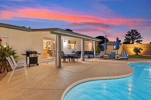 A poolside area with a covered patio, outdoor seating, and a barbecue grill. - Campus Palms | Modern 3BR | Private Pool (Tempe)