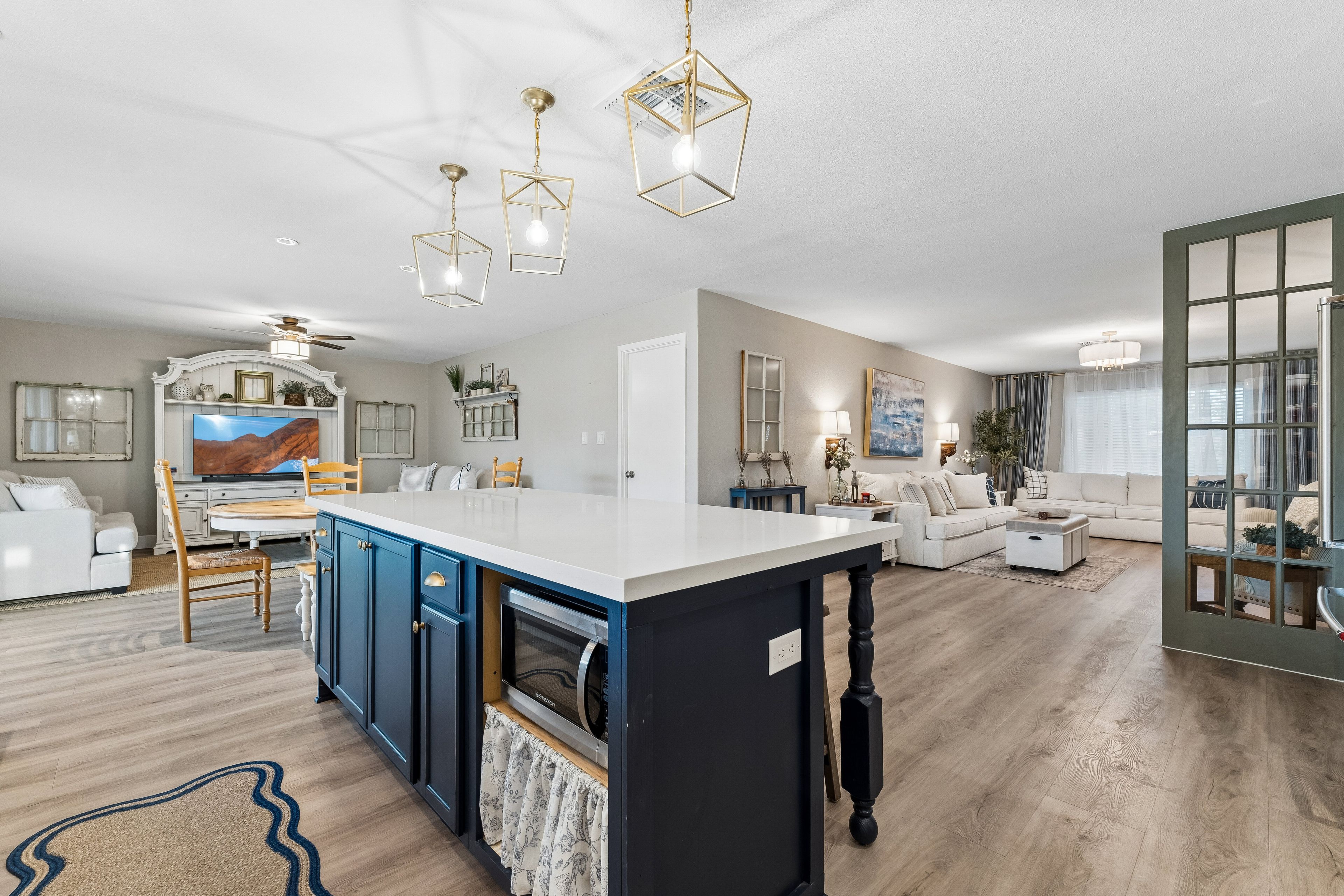 A modern kitchen with a central island, built-in appliances, and pendant lighting.