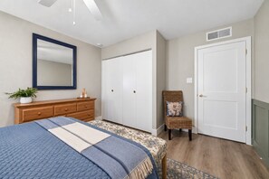 A bedroom with a bed, dresser, wardrobe, chair, and a mirror. - Campus Palms | Modern 3BR | Private Pool (Tempe)