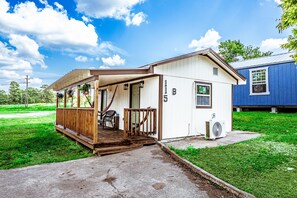 A small, single-story house with a porch, a small deck, and a yard.