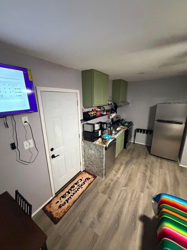 A compact kitchen with a refrigerator, microwave, and countertop appliances.