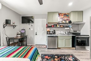 A compact kitchen with a dining area, a television, and a coffee bar.