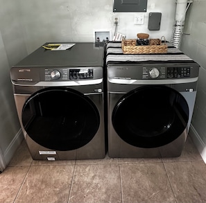 Two Samsung front-loading washing machines in a laundry room with tiled flooring. - Pleasant 3-bedroom house with AC in charming Cocoa (Cocoa)