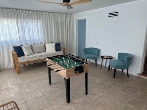 A room with a foosball table, a sofa, two chairs, and a ceiling fan. - Pleasant 3-bedroom house with AC in charming Cocoa (Cocoa)