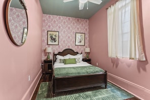 A bedroom with a bed, two bedside tables, a mirror, and two framed pictures on the wall. - A vibrant 3BR retreat built for making memories together. (New Orleans)
