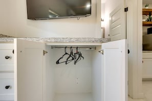 Een keuken met een granieten aanrecht, een ingebouwde magnetron en een hangende rek voor keukengerei.