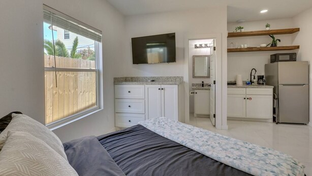 A bedroom with a bed, a window, and a view of a wooden fence. - #7 | Modern SPI Beach Studio + Pool | Smart TV (South Padre Island)