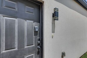 A dark-colored door with a keypad lock and a wall-mounted light fixture. - #7 | Modern SPI Beach Studio + Pool | Smart TV (South Padre Island)