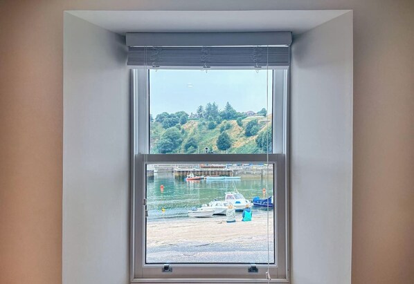 A room with a large window overlooking a hilly landscape and a marina with boats. - Harbour View Holiday Home at Stonehaven Harbour (Stonehaven)