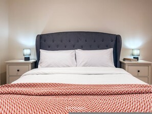 A bed with a tufted headboard, two bedside tables with lamps, and a patterned bedspread. - Harbour View Holiday Home at Stonehaven Harbour (Stonehaven)