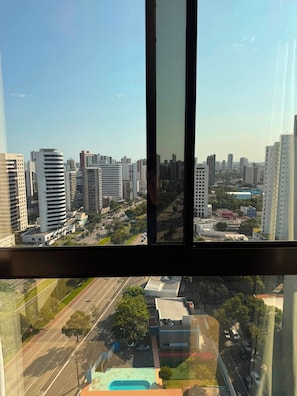 Un immeuble de grande hauteur offrant une vue sur le paysage urbain, avec plusieurs bâtiments imposants et une route où circulent des véhicules.