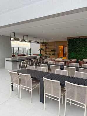 Un espace de restauration en plein air avec des tables et des chaises, un bar et une vue sur le paysage urbain.