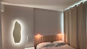 Een slaapkamer met een bed, nachtkastjes, een wandlamp en een gordijn.