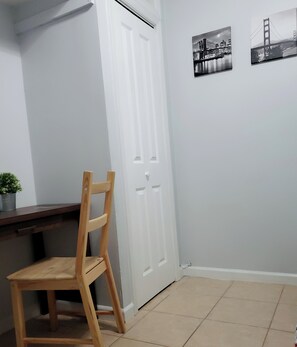 Ein Zimmer mit einem Holzstuhl, einer weißen Tür und zwei schwarz-weißen Fotografien an der Wand.