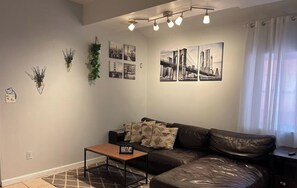 Ein modernes Wohnzimmer mit einer Couch, einem Couchtisch und Wandbildern, die Stadtansichten zeigen.