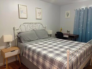 A bedroom with a bed, bedside table, desk, chair, and curtains. - Large Duplex home near NYC and Staten island with Parking (Bayonne)