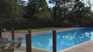 A swimming pool with a tiled deck, surrounded by trees and a grassy area. - Pet Friendly 2-Bed Lodge, Sleeps 5, Pool & Parking (Caernarfon)