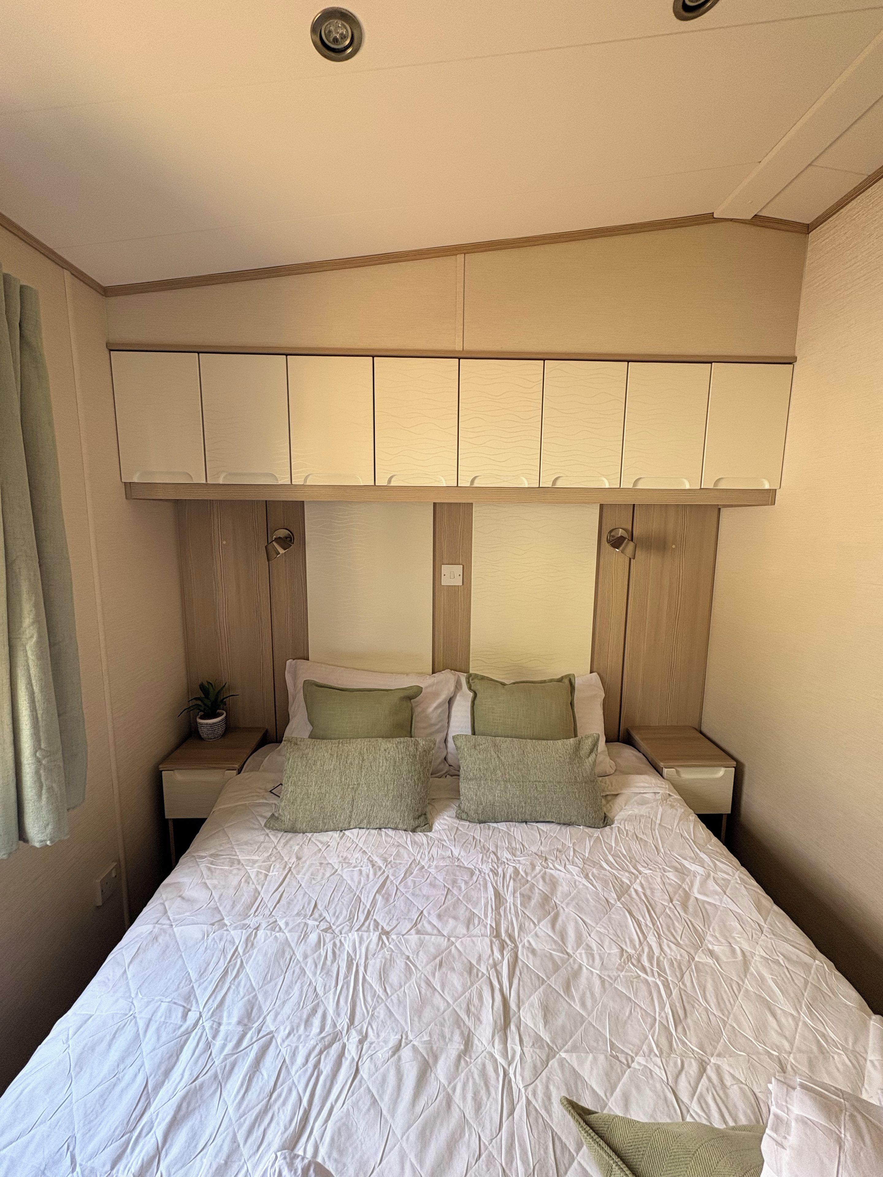 Un dormitorio con cama, mesita de noche, planta en maceta y armario empotrado.