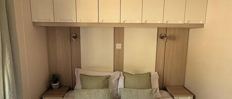 Un dormitorio con cama, mesita de noche, planta en maceta y armario empotrado.