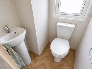 Un bagno piccolo e pulito con lavandino, WC e una finestra sopra il water.