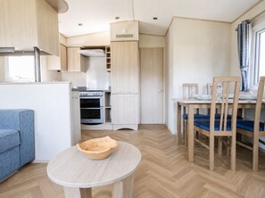 Una cuina compacta amb forn integrat, zona de dinar amb taula i cadires, i un petit seient amb sofà.
