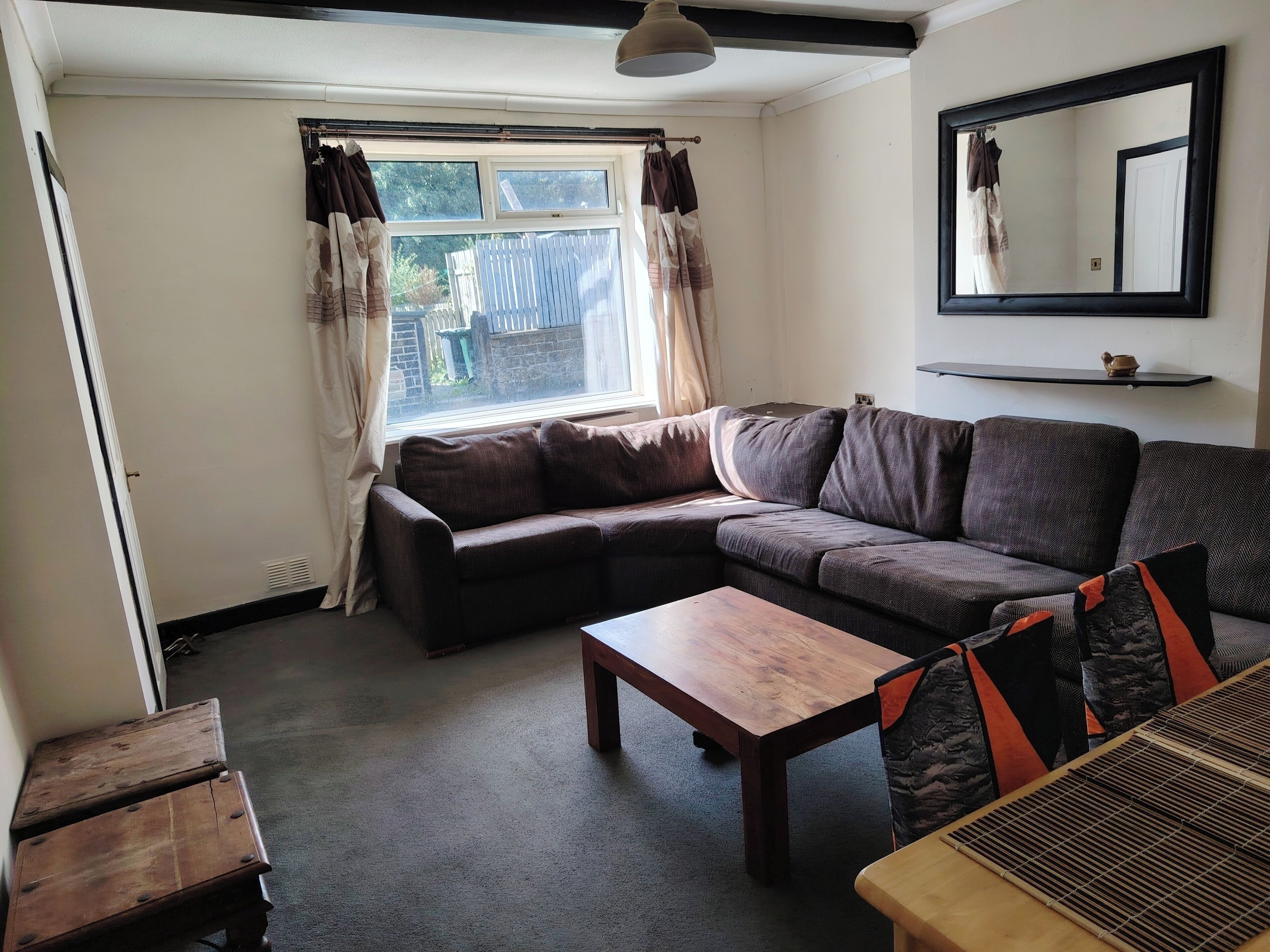 Una sala de estar con un sofá, una mesa de centro de madera y una ventana con cortinas.