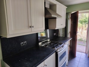 Una cocina con armarios blancos, encimera negra y estufa.