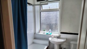 A bathroom with a bathtub, sink, toilet, and window. - Cosy Cottage Retreat in Huddersfield (Huddersfield)