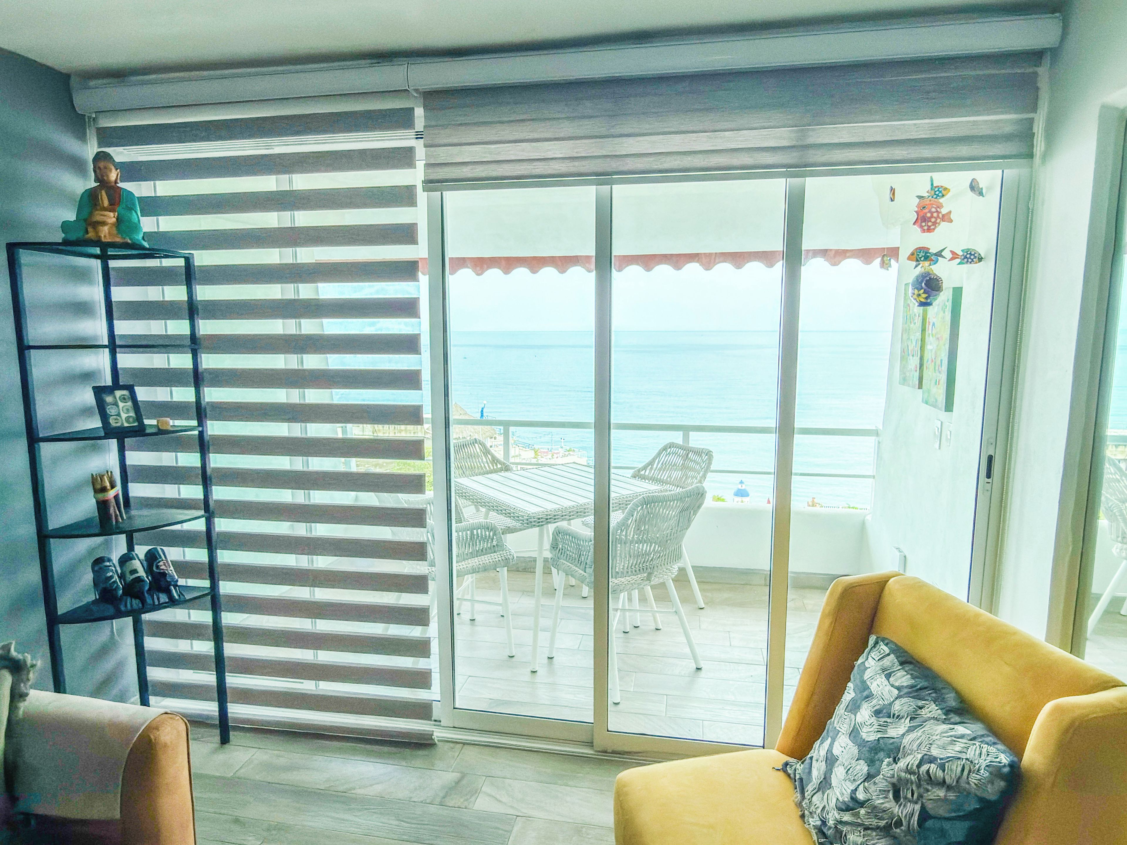 Una habitación con puerta de vidrio corredera que da a un balcón con vista al mar.