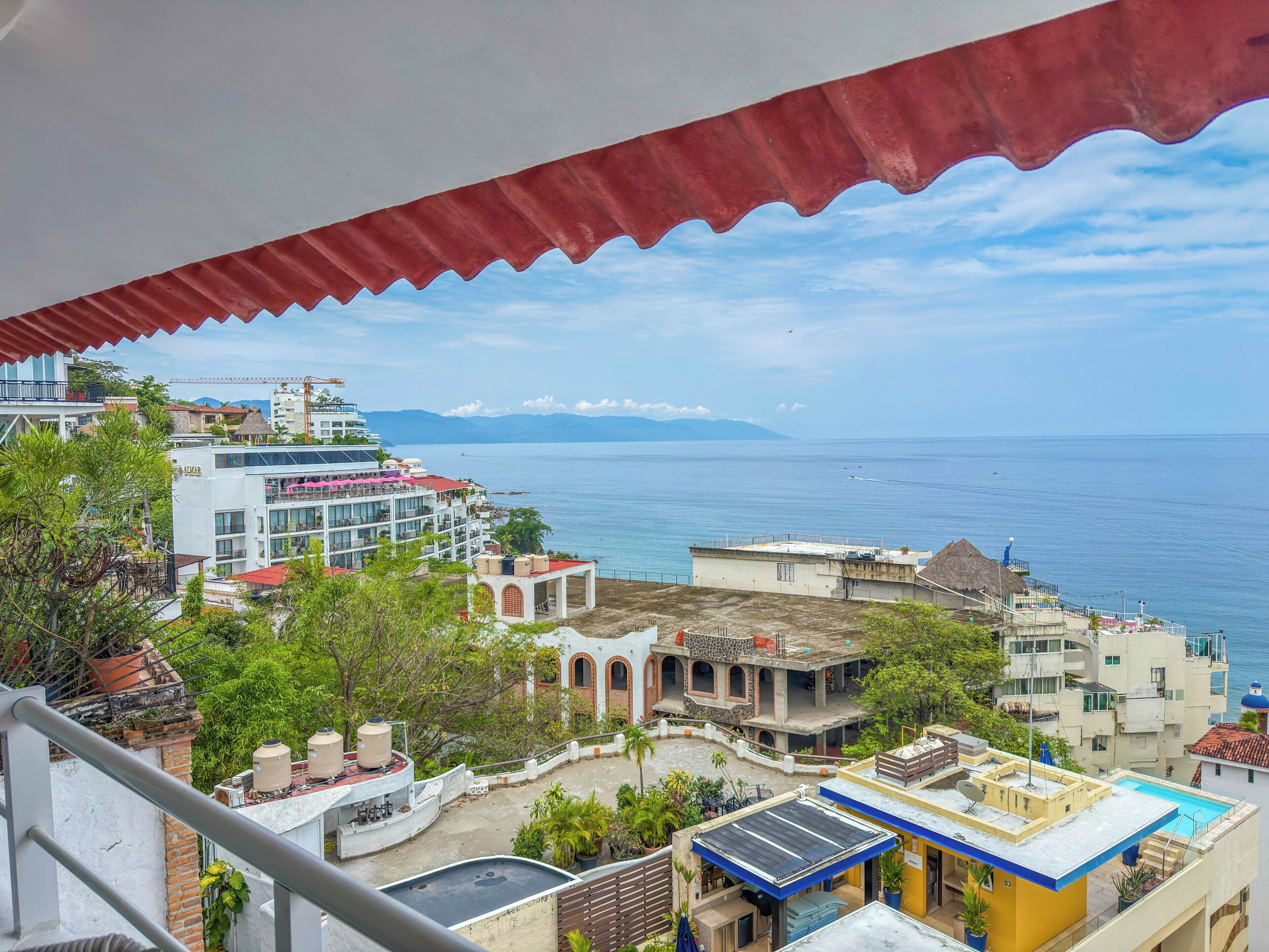 Un paisaje urbano costero con vista al mar, edificios con balcones y cielo despejado.
