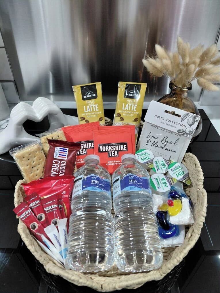 Ein Geschenkkorb mit verschiedenen Lebensmitteln und Getränken, darunter Yorkshire Tea, Nescafé Original und abgefülltes Wasser.