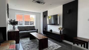 Ein modernes Wohnzimmer mit einer Couch, einem Couchtisch und einem Fernseher an der Wand.