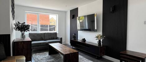 Uma sala de estar moderna com um sofá, mesa de centro e televisão na parede.