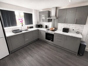 A modern kitchen with grey cabinets, a built-in oven, a microwave, and a toaster.