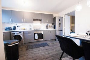Eine moderne Küche mit grauen Schränken, einem eingebauten Backofen, einer Mikrowelle und einem Geschirrspüler.