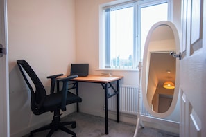 Una habitación pequeña con un escritorio, una silla y una ventana.